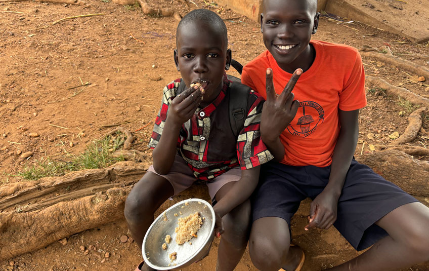 Two kids eating MannaPack Rice in Nakwanya, Uganda