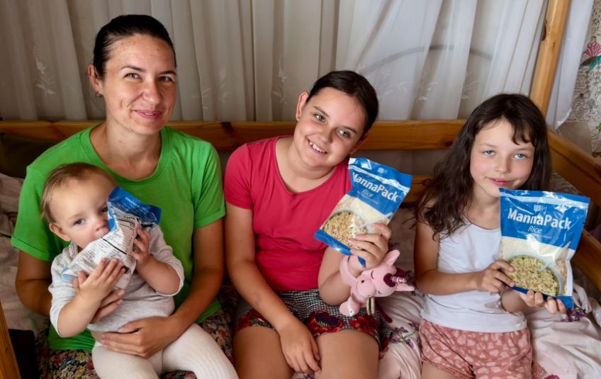 woman and three young girls in Ukraine holding bags of rice