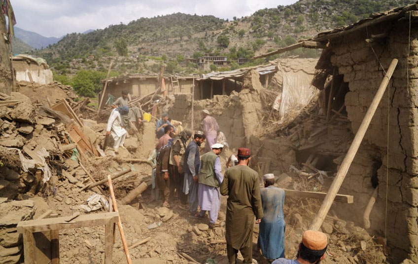A group of people amid damaged buildings following an earthquake in Afghanistan.