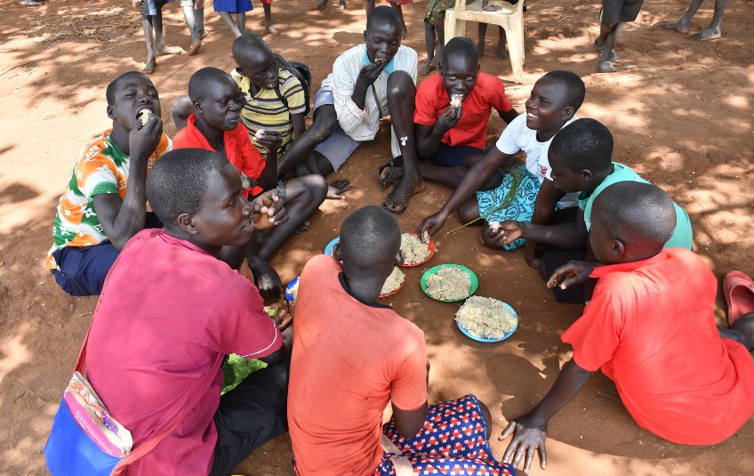 children in uganda eating in a circle on the ground