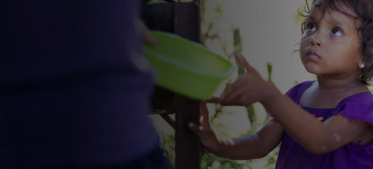 A girl hands an adult a bowl to be filled with FMSC food.